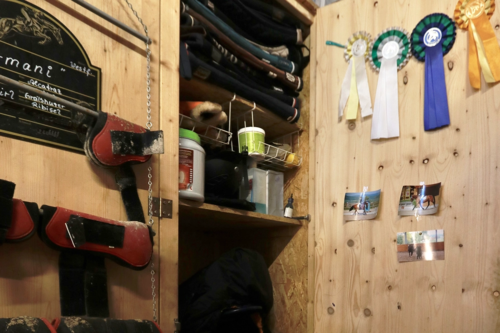 Offener Schrank in Sattelkammer, Fotos und Kokarden hängen an Tür