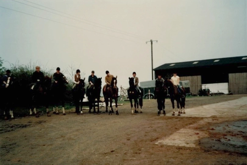 Altes Foto einer Gruppe von Reitern vor Stallgebäude