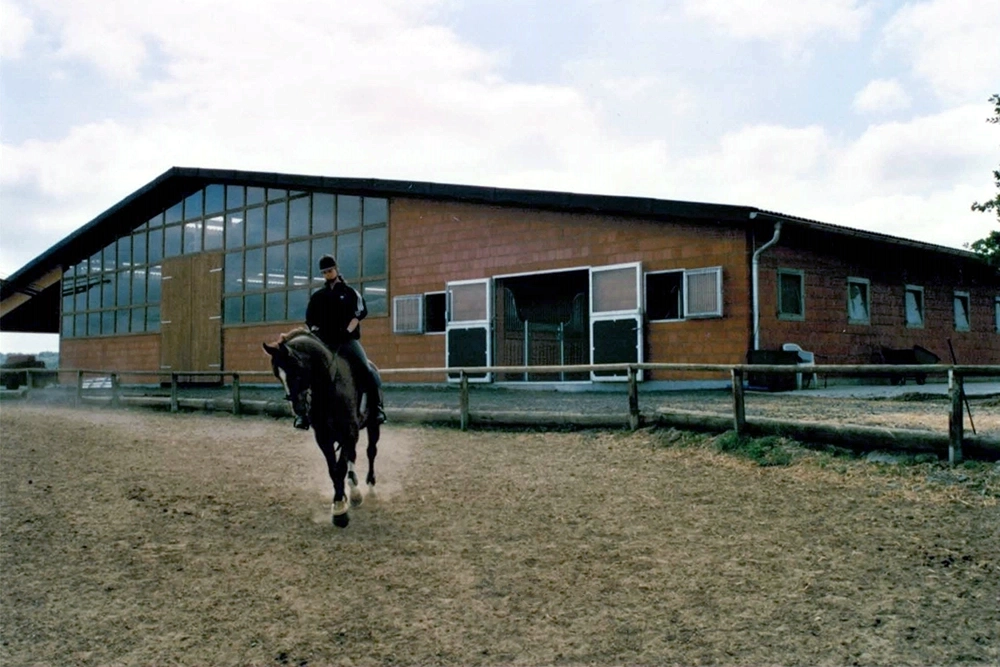 Reiterin auf Pferd vor Reithalle